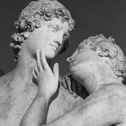Billedet er af to statuer, en mandlig og kvindelig. Den kvindelige statue har sin hånd på den mandlige statuer kind, samtidig med hun kigger elskværdigt på ham.