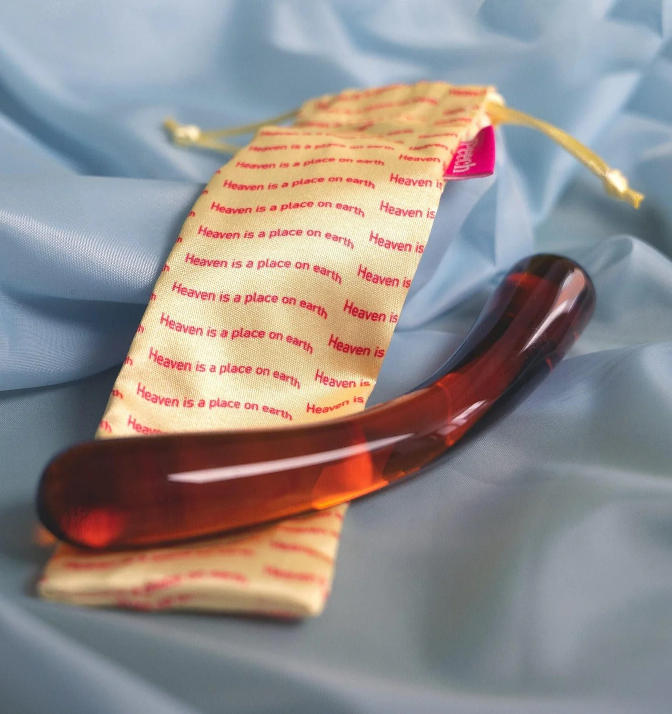 Billede af glas dildo placeret på et blåt stykke silke.