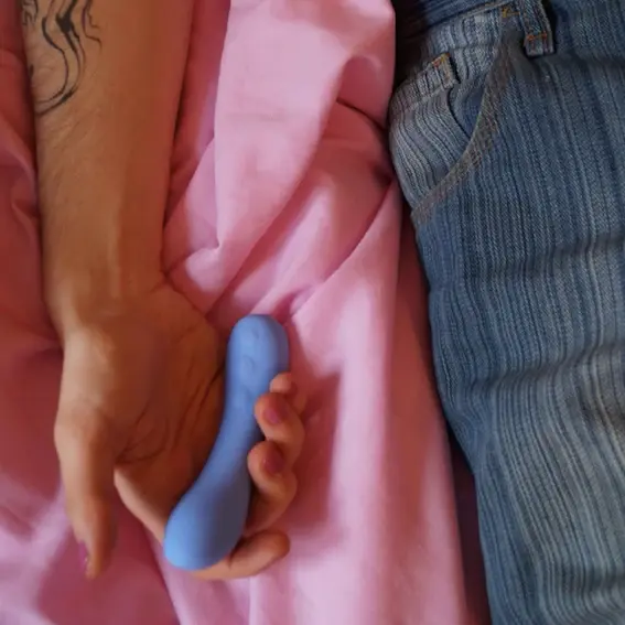 Peech June dildo Billede af mand i en seng, han holder en lille dildo i hånden.